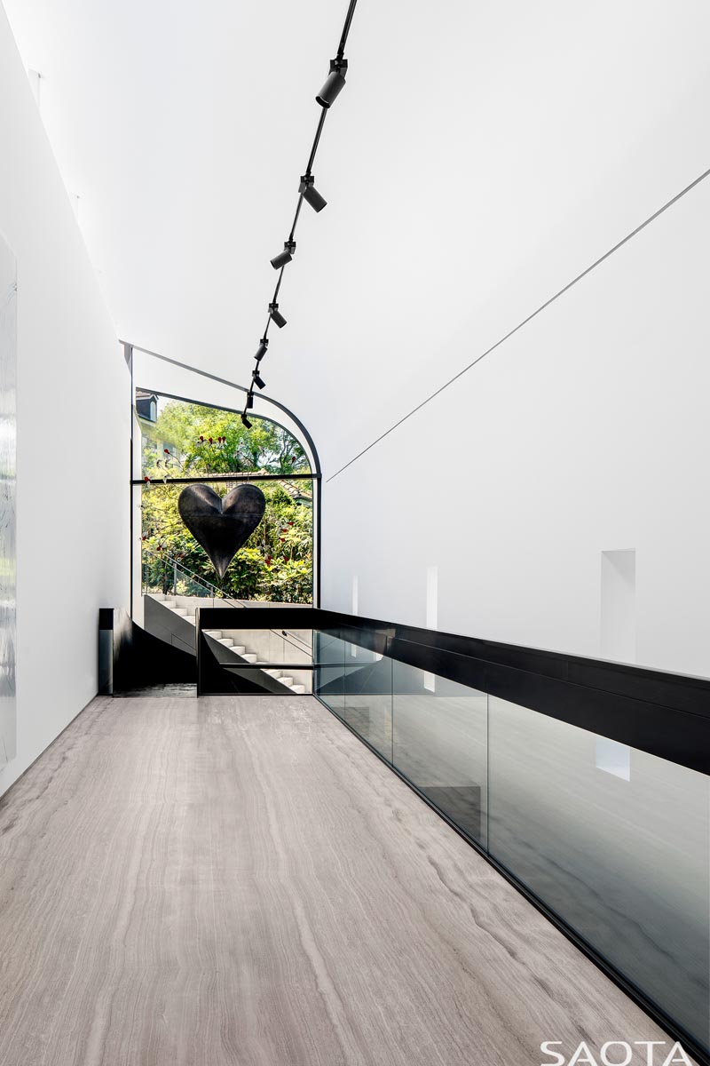 At the top of the stairs in this modern house is a window with views of the garden, and whose shape follows the line of the curved ceiling. #CurvedWindow #Windows #ModernHouse