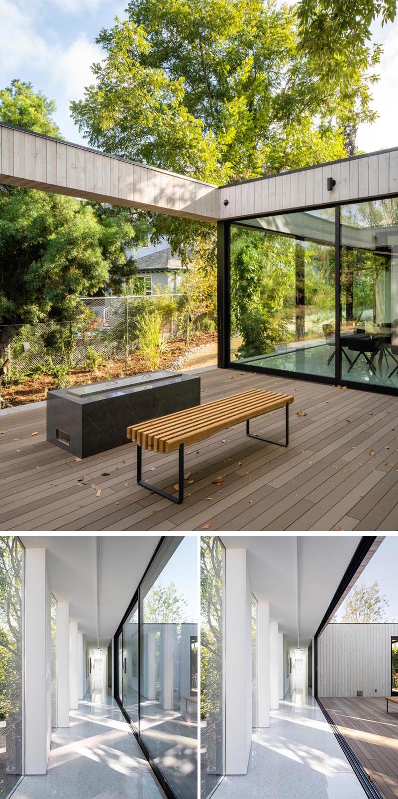 The glass walls in the dining room and hallway of this modern house slide open to give access to a deck that's home to an outdoor fire. #GlassWalls #Deck #Hallway #Windows