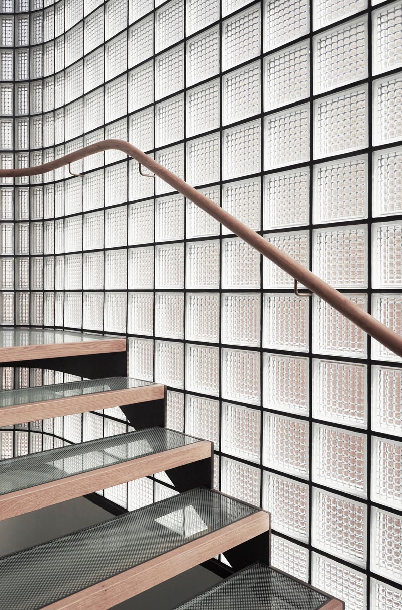 This modern house features a stairwell surrounded by glass blocks with black grout, and steel, wood, and glass treads. #ModernGlassBlock #GlassBlock #Stairs #Stairwell