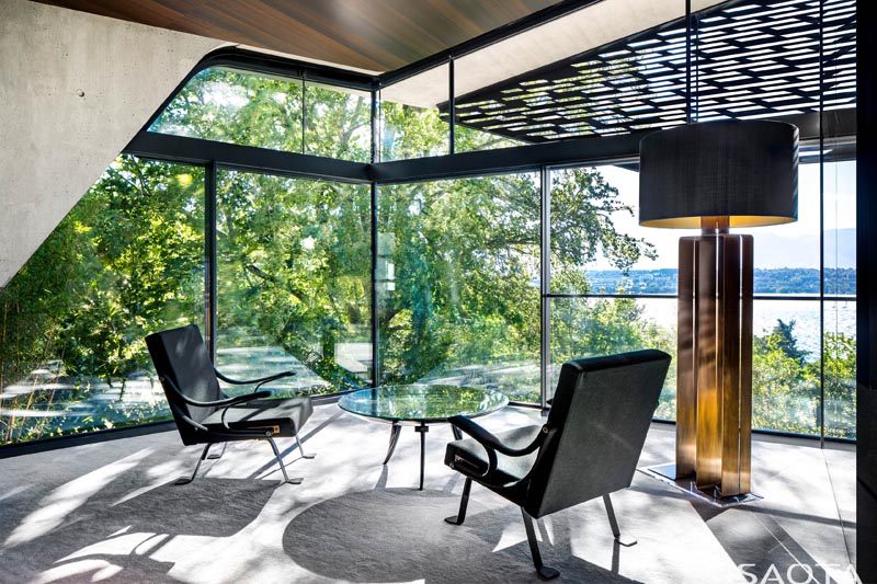 This modern home office takes advantage of the spectacular views, and enjoys the shade from the trees and the perforated screen on the exterior of the house. #ModernHomeOffice #GlassWalls