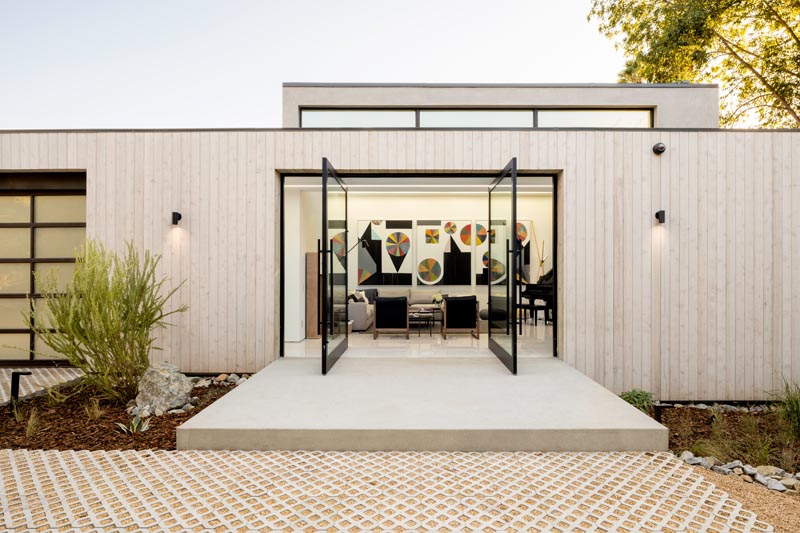 Welcoming visitors to this modern house are a pair of pivoting glass front doors that lead straight into the living room. #FrontDoor #GlassFrontDoor #PivotingDoor