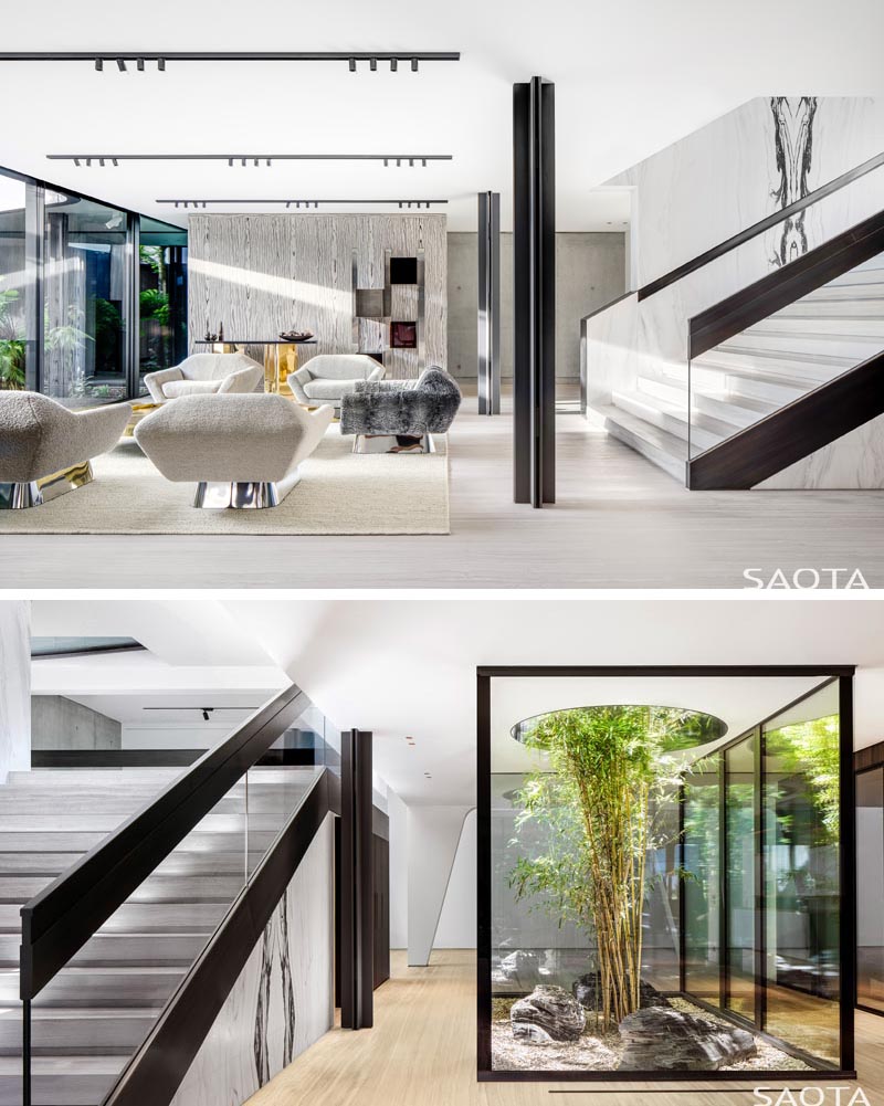 This modern house has a secondary living room and a small interior garden surrounded by glass, has a tree that's grown up through a circular opening. #InteriorGarden #LivingRoom #Stairs