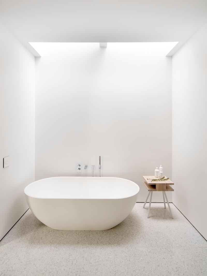 In this modern master bathroom, the freestanding bathtub is located directly below skylights, allowing the user to look up to the sky as they relax. #Bathroom #MasterBathroom #WhiteBathroom