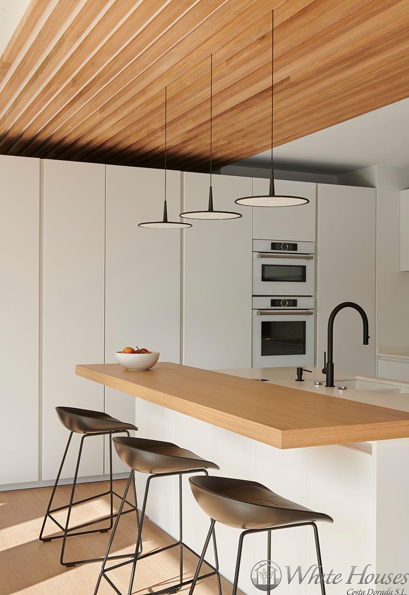 In this modern kitchen, white appliances have been chosen to blend in with the surrounding minimalist white cabinets, helping to create a somewhat seamless appearance. #WhiteKitchen #ModernKitchen #KitchenDesign