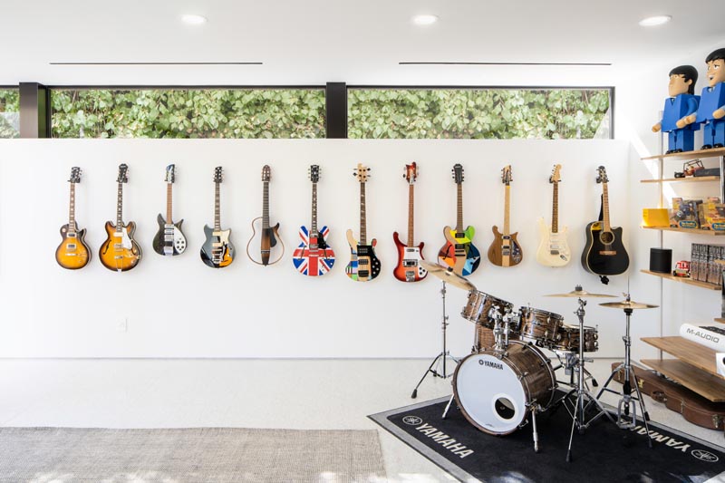 This modern house has a music room furnished with a drum kit and a wall of guitars. #MusicRoom #ModernInterior