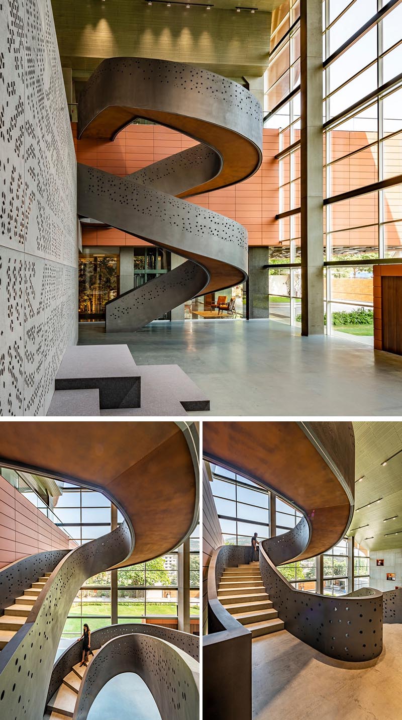 This modern workplace showcases a perforated pattern on the spiral staircase that connects all three levels of the office. The grey exterior of the stairs, with its scattered circle pattern, is reciprocated on the interior of the stairs, allow people to enjoy the pattern while they travel between the levels. #SpiralStairs #Workplace #OfficeDesign #PerforatedPattern