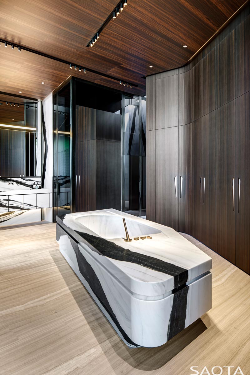 In this modern bathroom, tall wood closets line the wall, while a stone bathtub is centrally located. #ModernBathroom #BathroomDesign #StoneBathtub