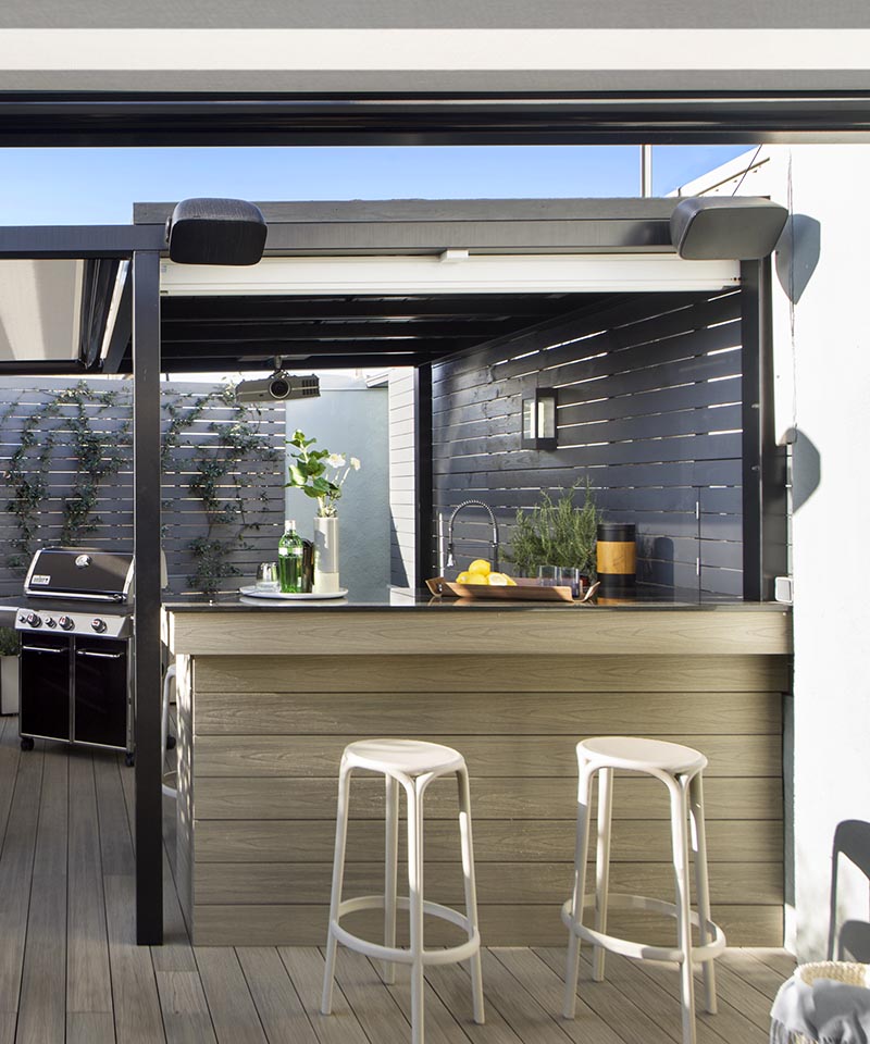 This modern outdoor terrace has a bar area with seating. A hidden detail is the white screen that can be pulled down to show a movie on. #Terrace #OutdoorBar #Projector