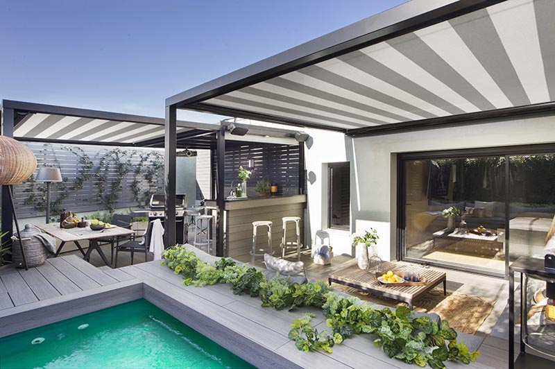 This modern terrace has shade cloths with a striped pattern that add another design element to the space, complementing the black and grey accents used throughout the outdoor space. #ShadeClothes #Terrace #Outdoor Entertaining #SwimmingPool