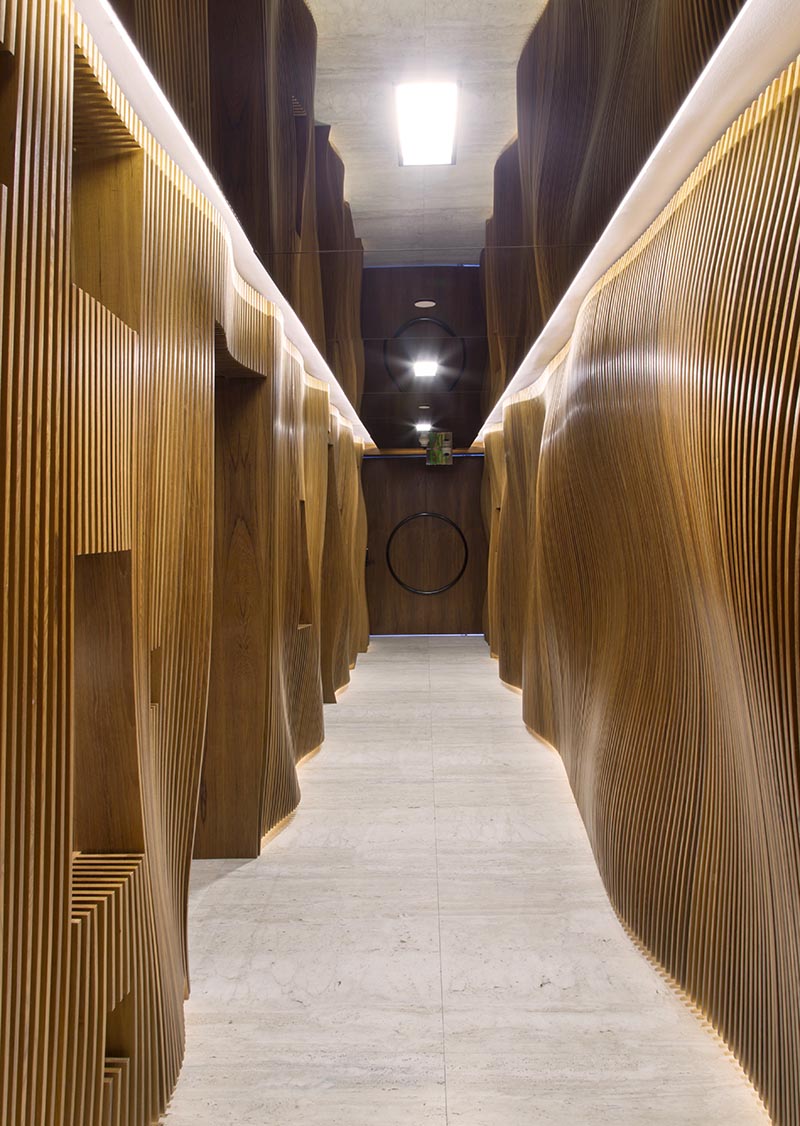 Fernanda Marques Arquitetos Associados has designed an apartment in Miami, Florida, and as part of the design, they included an eye-catching sculptural wood hallway with a mirrored ceiling. #WoodHallway #SculpturalHallway #WavyWoodWall #InteriorDesign #MirroredCeiling
