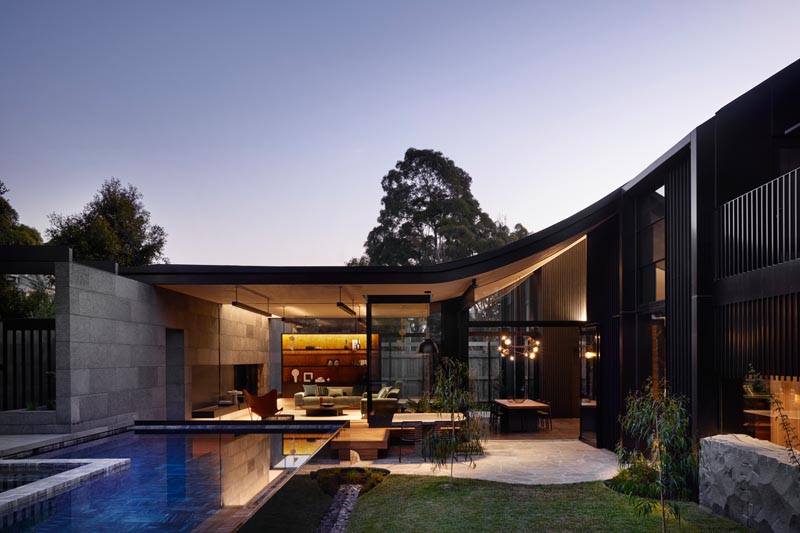 This modern house has a living room that connects to an outdoor space with a yard and swimming pool. #Architecture #OutdoorSpace #Landscaping #SwimmingPool