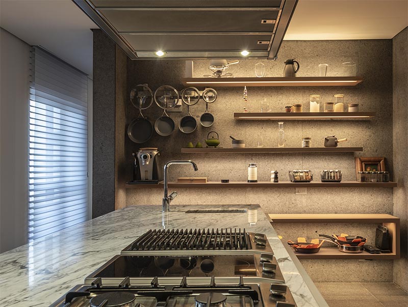 These modern floating wood shelves, which are all different lengths, have a strip of hidden lighting underneath, highlighting the various displayed items, as well as adding ambient lighting and a dramatic touch to the kitchen. #KitchenShelves #Shelving #Shelves #FloatingShelves #HiddenLighting