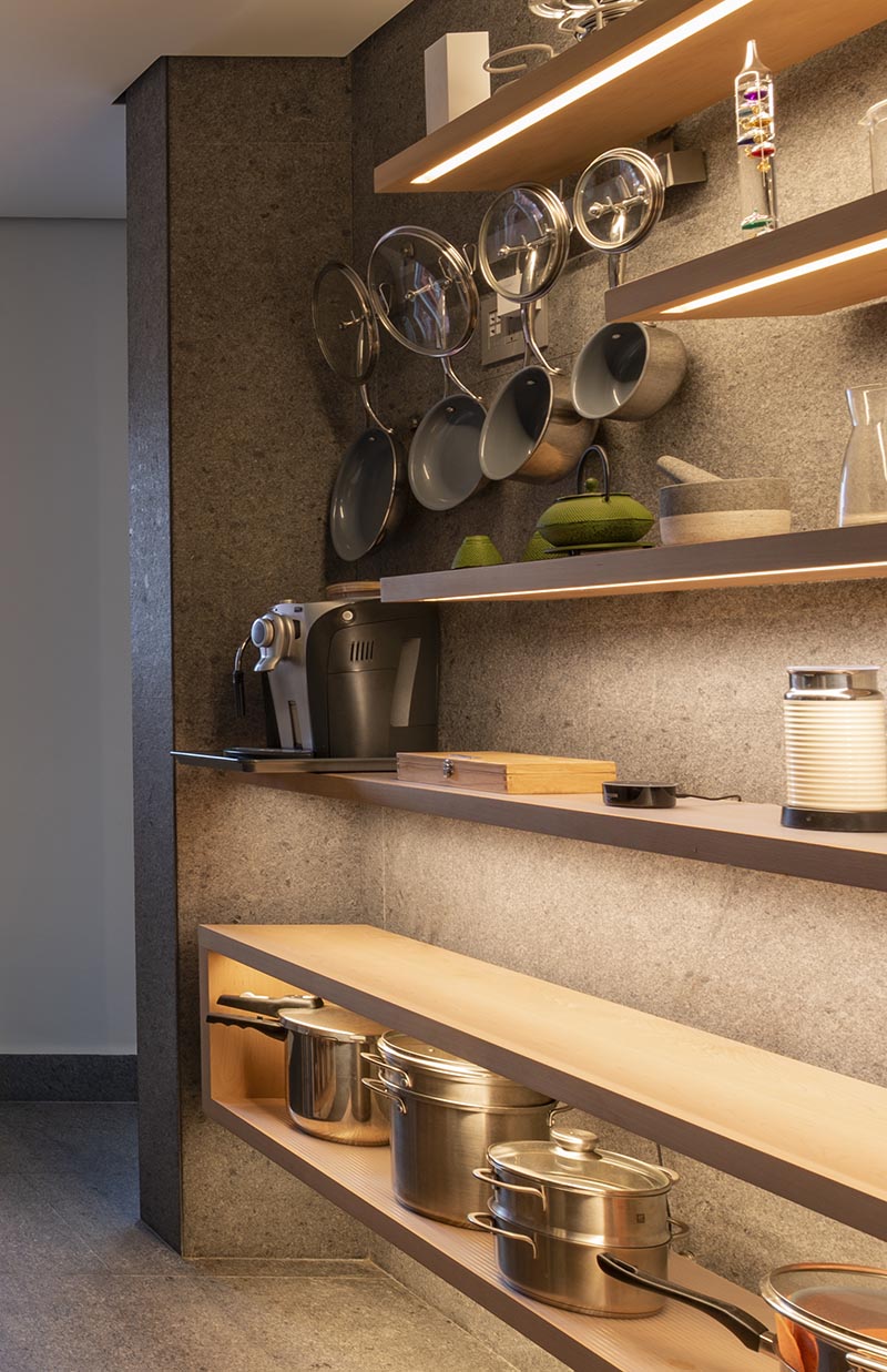 These modern floating wood shelves, which are all different lengths, have a strip of hidden lighting underneath, highlighting the various displayed items, as well as adding ambient lighting and a dramatic touch to the kitchen. #KitchenShelves #Shelving #Shelves #FloatingShelves #HiddenLighting