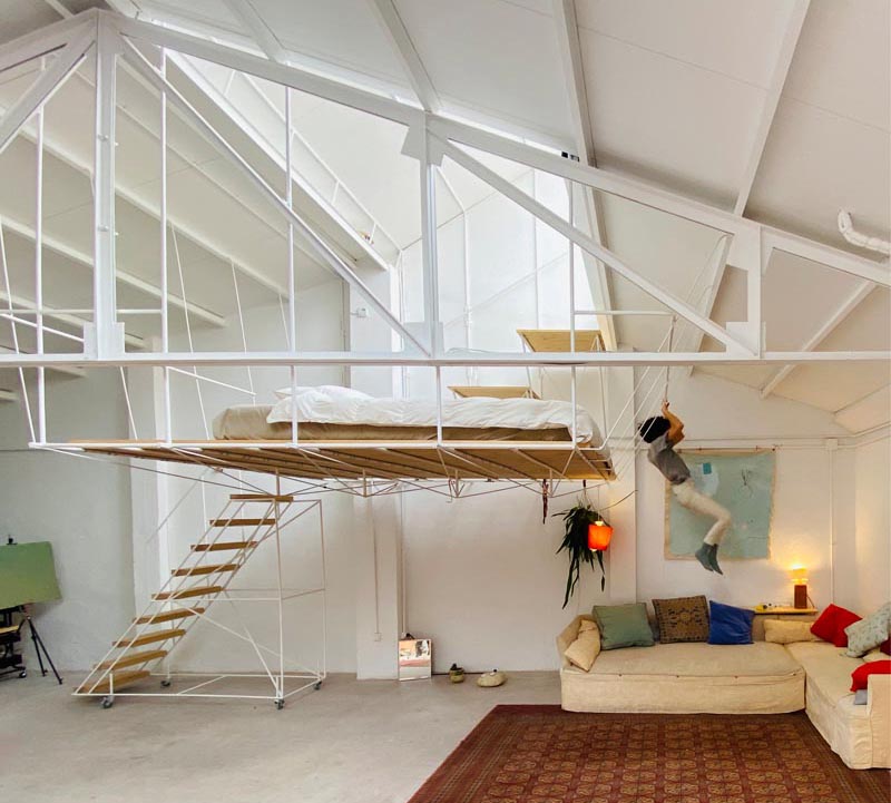 This open plan minimalist apartment was a former warehouse, and features a hanging platform bed made from steel and wood. #PlatformBed #HangingBed #InteriorDesign #BedroomDesign