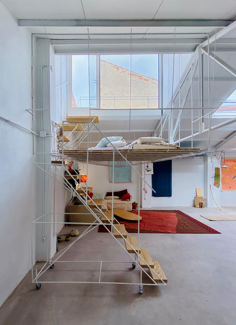 This open plan minimalist apartment was a former warehouse, and features a hanging platform bed made from steel and wood. #PlatformBed #HangingBed #InteriorDesign #BedroomDesign