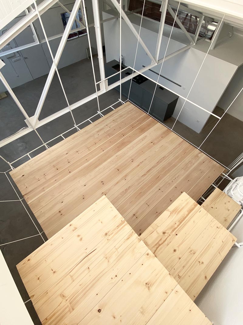 This open plan minimalist apartment was a former warehouse, and features a hanging platform bed made from steel and wood. #PlatformBed #HangingBed #InteriorDesign #BedroomDesign