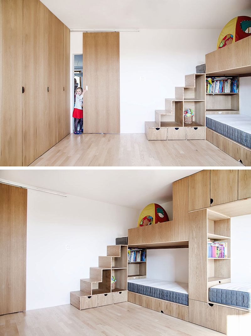 This modern kids bedroom has high ceilings, a sliding wood door, an open space for play, a wall of cabinets, and a bunk bed designed for three. #BunkBed #KidsRoom #ChildrensBedroom #Cabinets #BedDesign
