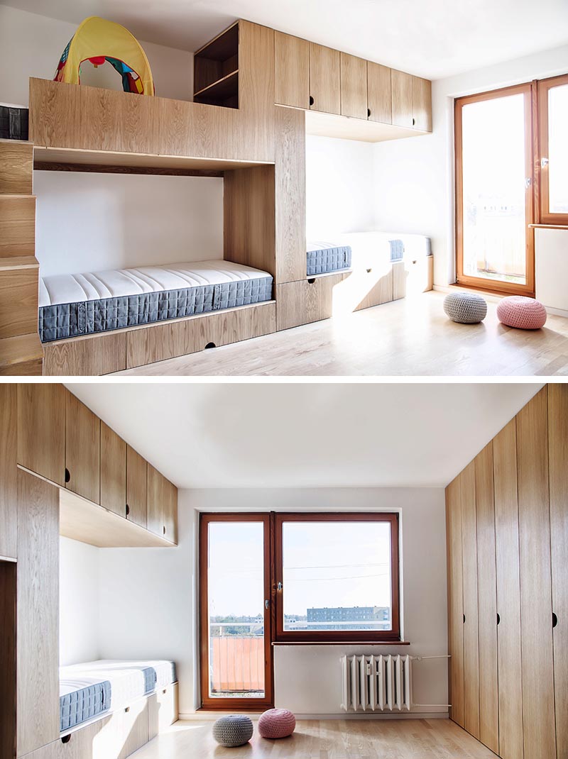 This modern kids bedroom has high ceilings, a sliding wood door, an open space for play, a wall of cabinets, and a bunk bed designed for three. #BunkBed #KidsRoom #ChildrensBedroom #Cabinets #BedDesign