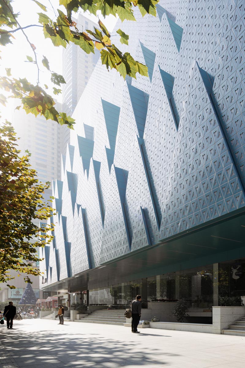 Layers of perforated aluminum plates in the shape of mountains were designed to create a background for the street trees and symbolize the new life of the Hubei Foreign Language Bookstore. #Architecture #FacadeDesign #BuildingDesign