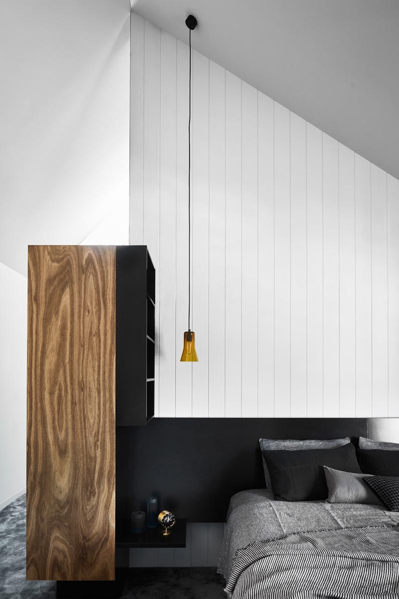 In this modern bedroom, a wood accent adds a natural touch to the black and white interior. #ModernBedroom #BedroomDesign