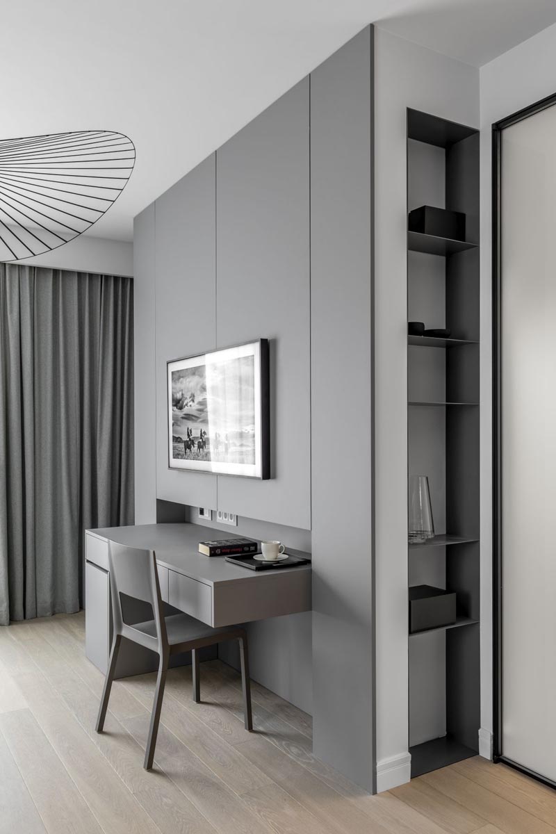 This minimalist grey wall has a built-in desk and shelving niche. #DeskIdeas #ShelvingNiche #GreyWall