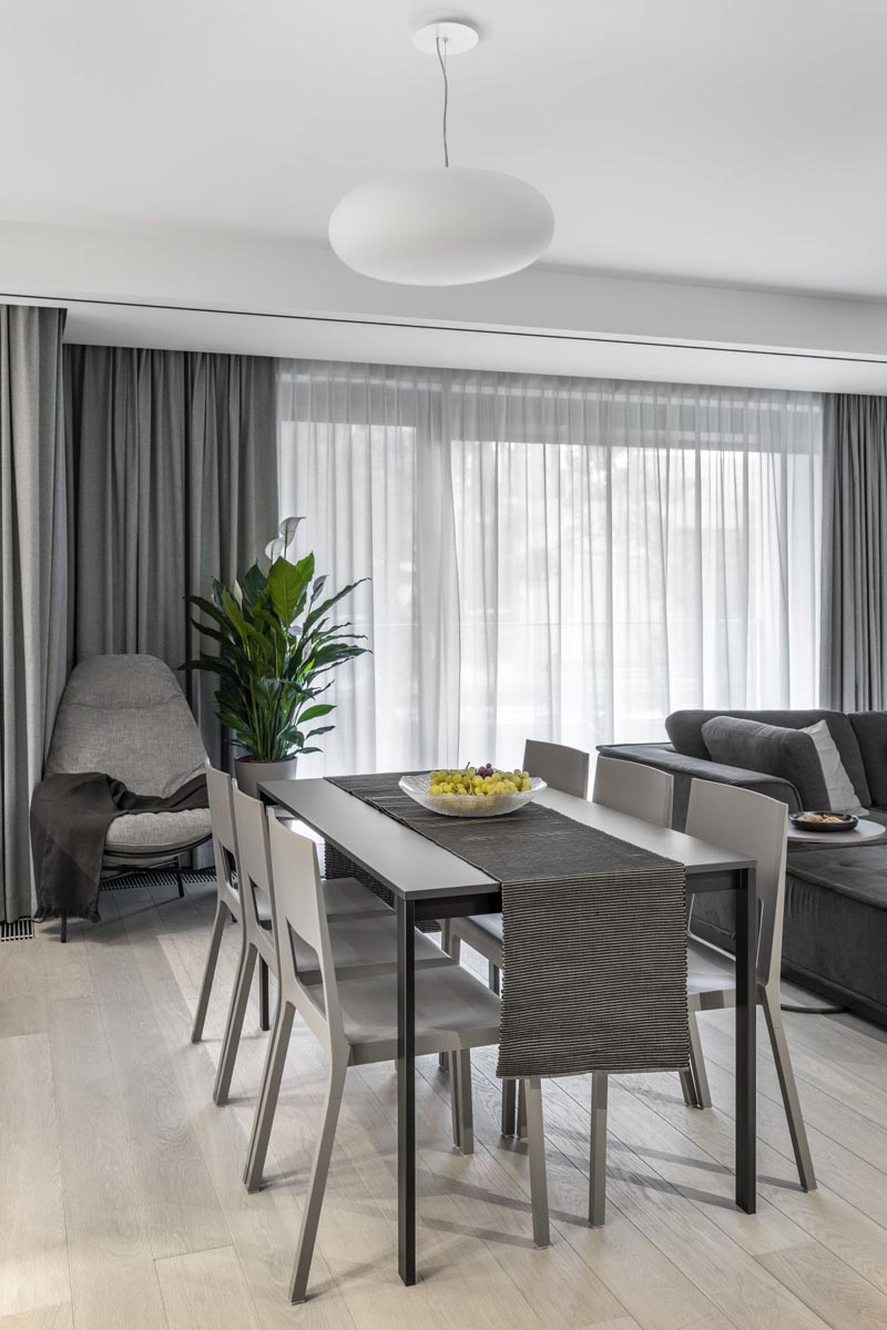 In this modern dining area, a touch of green has been added with a plant, while the floor to ceiling curtains provide privacy and soften the interior. #DiningRoom #GreyCurtains #InteriorDesign