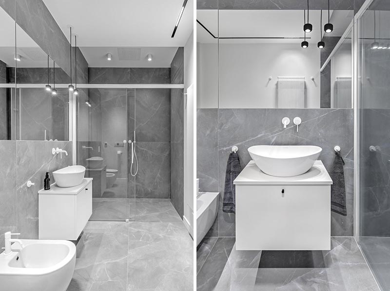 In this modern bathroom, large format grey tiles cover the walls and floors, while a floating white vanity complements the faucets and hardware. #ModernBathroom #BathroomDesign #GreyBathroom