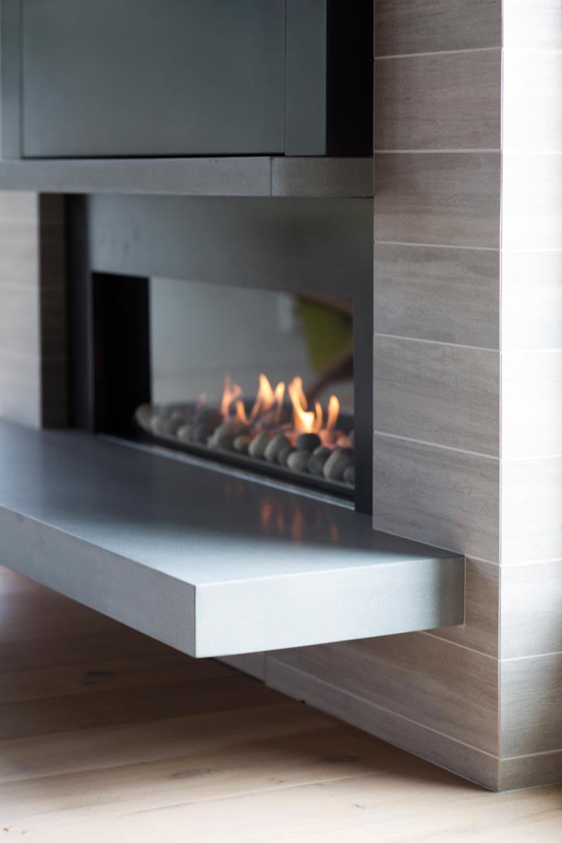 A linear fireplace with a cantilevered hearth and wood-grain tiles.