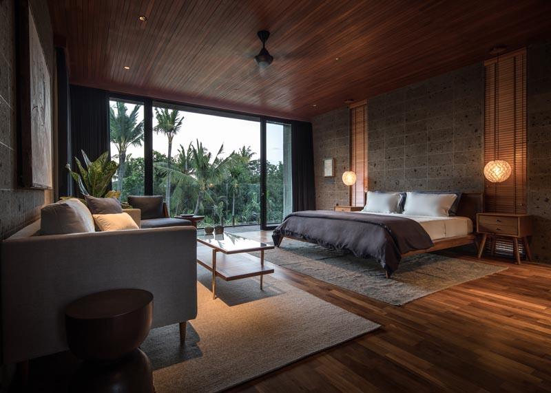 In this modern bedroom, a dark wood ceiling, as well as wood floors and wood blinds adds a sense of warmth to the room. #ModernBedroom #WoodAndGrey #BedroomDesign