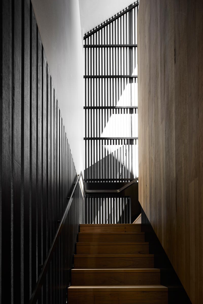 Dark stairs surrounded by blackened wood slats connects the various floors of this modern house. #Stairs #ModernInterior #ModernStairs