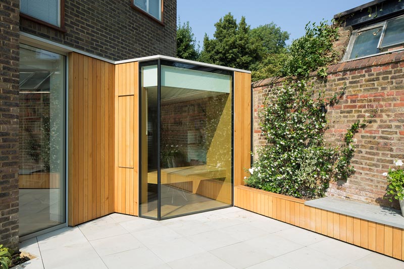 This modern home office design is a spacious and light filled extension that features a folding facade of glass and oak, while inside there's custom designed bookshelves and two desks. #HomeOffice #HomeOfficeDesign #Architecture