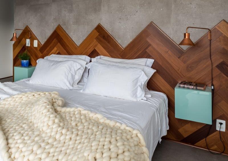 This modern wood headboard, with its different shades of wood laid in a herringbone pattern, travels the entire length wall, adding visual interest to the room, and softening the concrete wall and floor of the bedroom. #WoodHeadboard #Herringbone #ModernBedroom #HeadboardIdeas