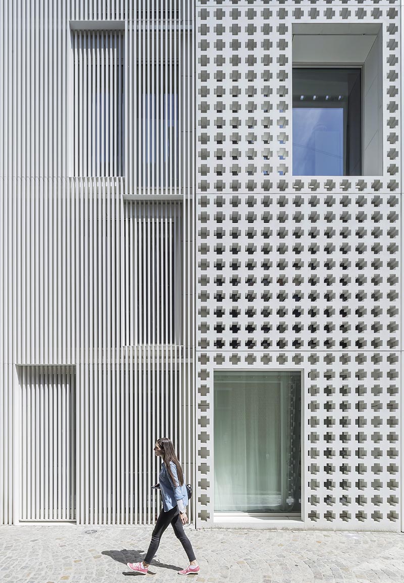 The cross-pattern facade of this modern buidling is made from pre-cast concrete and due to the design of the building, it's located between two other materials - white plaster and aluminum slats. #ModernArchitecture #ModernBuilding #PatternedFacade