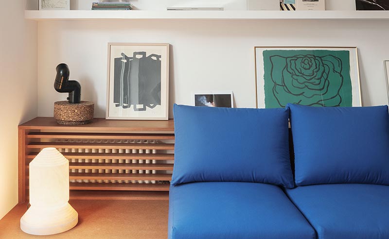 A custom designed shelving unit with a wood slat front is used to hide the radiator in plain sight in this modern apartment. #HideRadiator #Radiator #LivingRoom