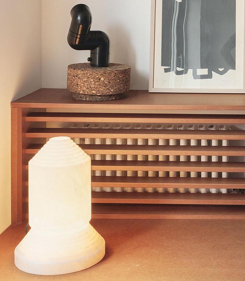 A custom designed shelving unit with a wood slat front is used to hide the radiator in plain sight in the living room of this modern apartment. #HideRadiator #Radiator #LivingRoom