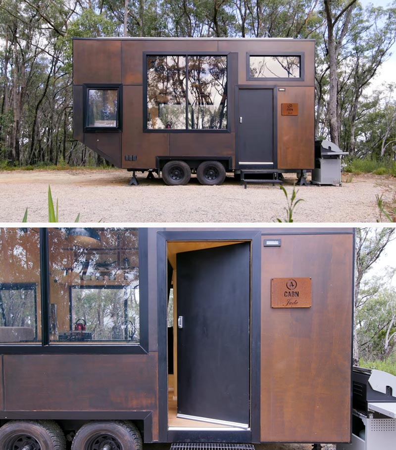 Designed as a getaway for city dwellers to relax in the wilderness, this modern tiny house features an exterior of intentionally mismatched stained panels of marine ply, allowing it to withstand the weather conditions and blend in with the surrounding landscape. #TinyHouse #TinyHome #ModernTinyHouse #BlackWindowFrames