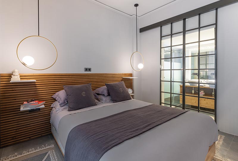 This modern bedroom features a wood slat headboard with shelves that act as bedside tables. #ModernBedroom #HeadboardDesign #WoodSlatHeadboard #BedsideTable #BedroomDesign