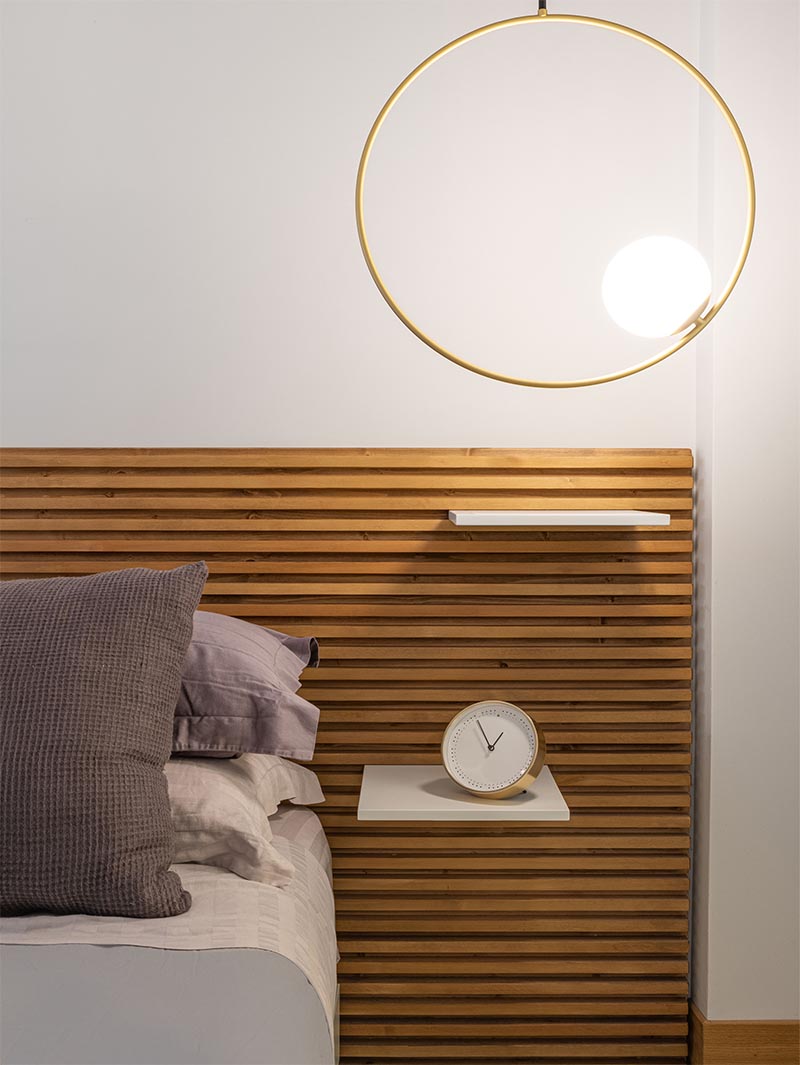 This modern bedroom features a wood slat headboard with shelves that act as bedside tables. #ModernBedroom #HeadboardDesign #WoodSlatHeadboard #BedsideTable #BedroomDesign