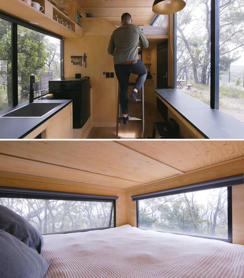 In this modern tiny house, a ladder provides access to the loft that features a king size bed. Black roller blinds can be closed for privacy when needed. #TinyHouseLoft #TinyHouseBed #TinyHouseWindows