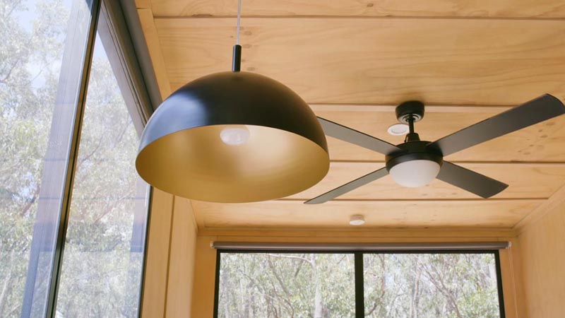 Black accents throughout this modern tiny home, like switches, window frames, and lighting, create a strong contrast to the light wood interior. #TinyHouse #TinyHome #Lighting #Fan