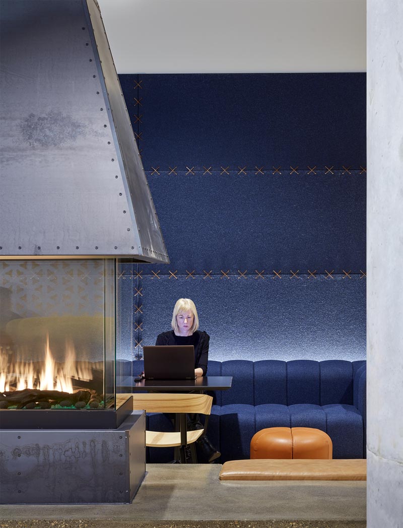 Studio BV has recently completed a lobby fireplace lounge that features rich blue felt wall panels that are stitched together with leather strips, complementing the custom-designed blue sofa and leather accents. #FeltWallPanels #FeltWallCovering #OfficeDesign #LobbyDesign #WorkplaceDesign #FeltPanels