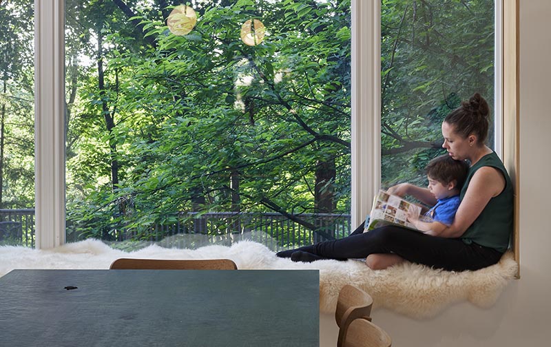 Lined with wood and cushioned with sheepskin, this modern built-in window seat looks out to the tall trees in the garden. #WindowSeat #ModernInterior #InteriorDesign