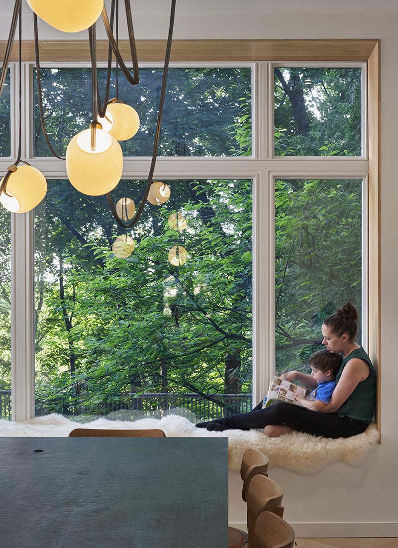 Lined with wood and cushioned with sheepskin, this modern built-in window seat looks out to the tall trees in the garden. #WindowSeat #ModernInterior #InteriorDesign