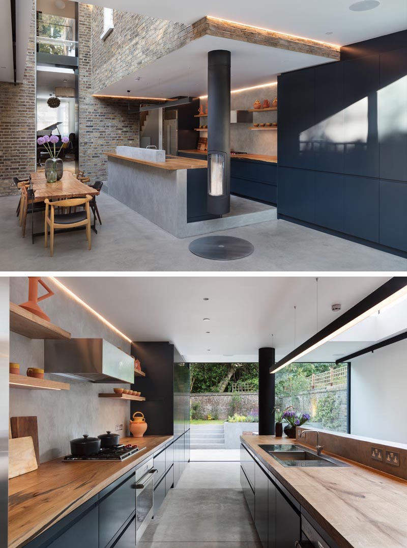 Designed with entertaining in mind, this modern house extension allowed for the creation of a living space, dining area, and a slightly raised modern kitchen with dark cabinets, concrete floors, and a oak countertops. #DarkKitchen #WoodCountertop #ConcreteFloor #DarkCabinets #KitchenDesign