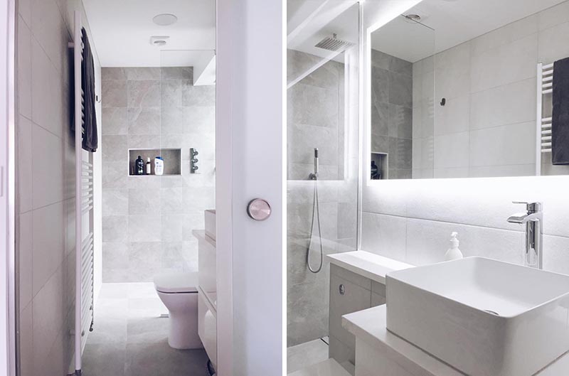 This modern en-suite bathroom features a walk-in shower with a built-in shower niche, and a backlit mirror is mounted above the vanity. #BacklitMirror #ModernBathroom #ShowerNiche