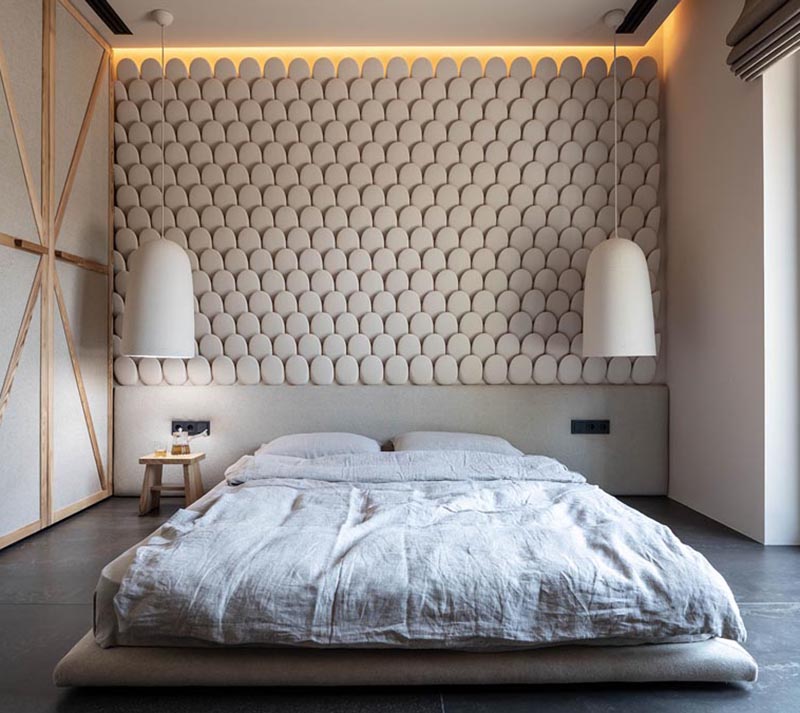 This modern bedroom features an eye-catching accent wall, that looks like small rounded stones, and helps to add texture to the room. #AccentWall #ModernBedroom #SculpturalWall #BedroomDesign