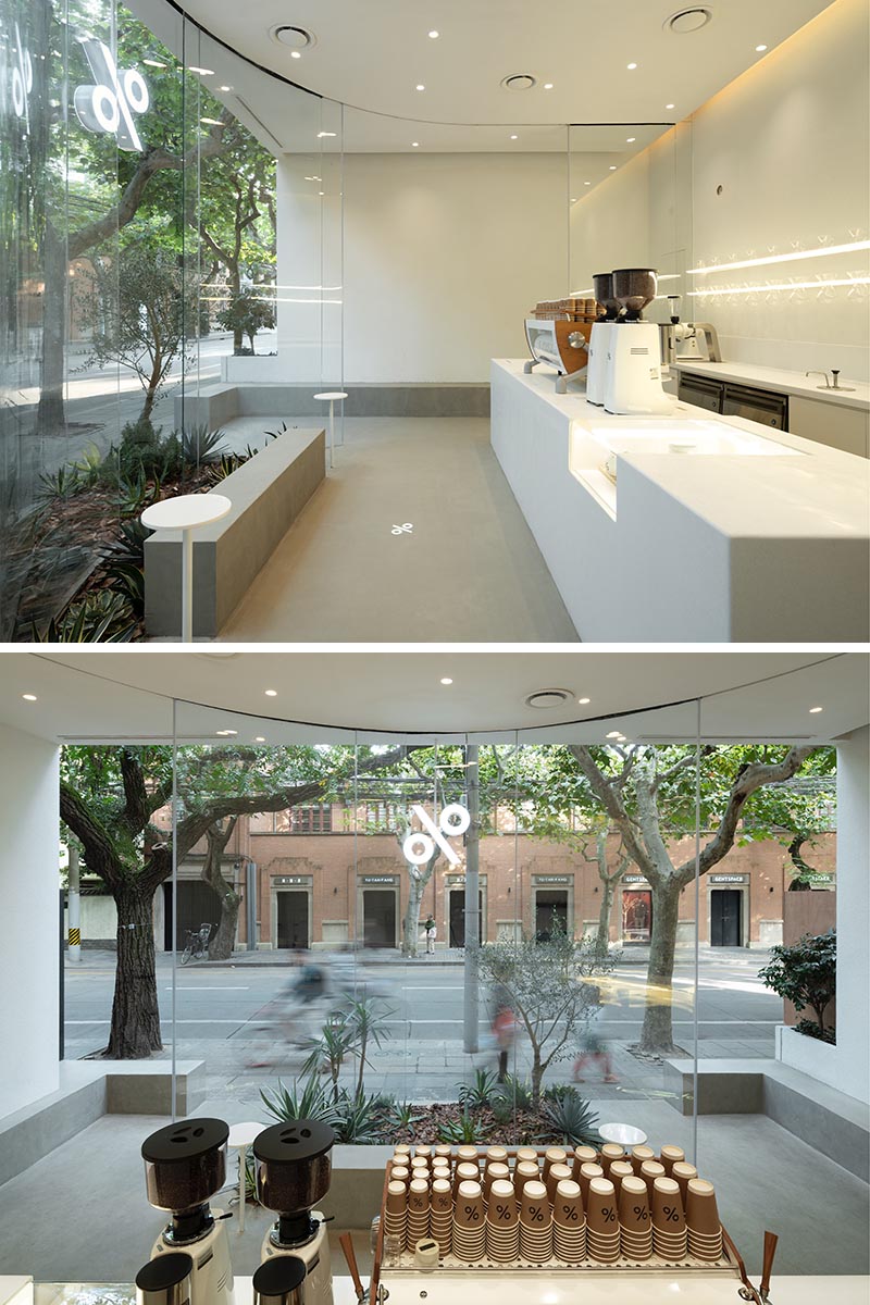 The curved glass door openings on both sides of this modern coffee shop allows customers to order and then move through to the other side, where they can pick up their coffee and sit on the partially covered benches outside. #CoffeeShop #ModernCoffeeShop #ModernCafe #CurvedGlass #RetailDesign