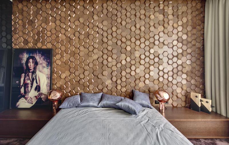 This modern bedroom has an eye-catching accent wall made from 3-dimensional hexagonal wood tiles in a honeycomb pattern. #WoodTiles #WoodAccentWall #3DAccentWall #BedroomDesign #InteriorDesign