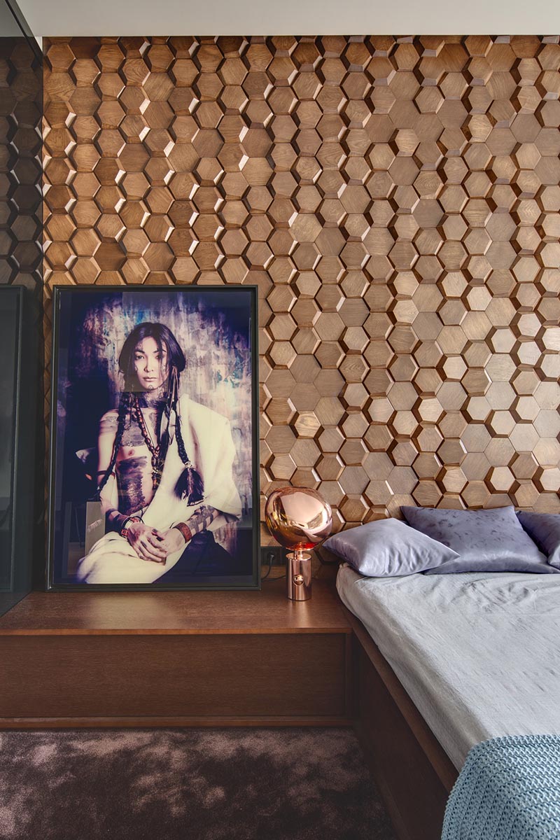 This modern bedroom has an eye-catching accent wall made from 3-dimensional hexagonal wood tiles in a honeycomb pattern. #WoodTiles #WoodAccentWall #3DAccentWall #BedroomDesign #InteriorDesign