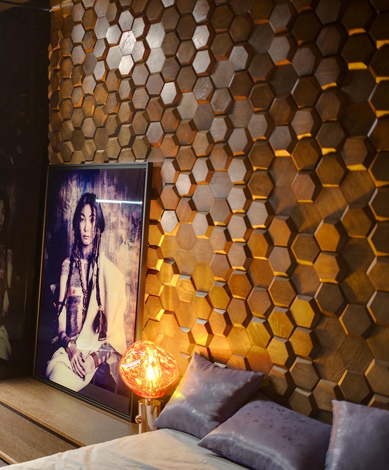 This modern bedroom has an eye-catching accent wall made from 3-dimensional hexagonal wood tiles in a honeycomb pattern. #WoodTiles #WoodAccentWall #3DAccentWall #BedroomDesign #InteriorDesign